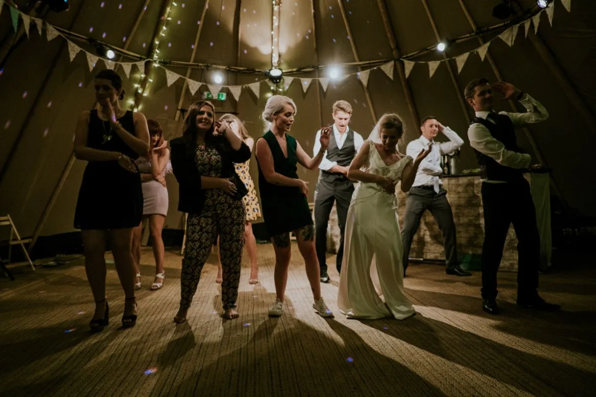 People at reception dancing to the macarena being played by the wedding DJ