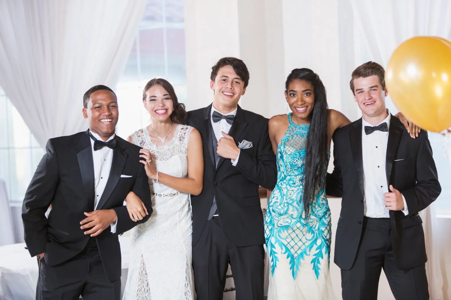 Happy young people with balloons at high school prom